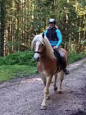 Elfriede Krauß auf dem Rücken eines Pferdes beim Ritt durch einen Wald